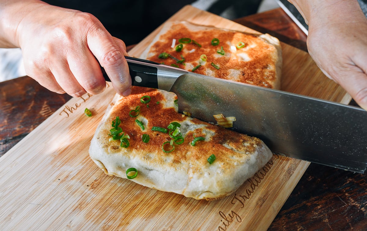 cutting Chinese meat pie with a knife on cutting board