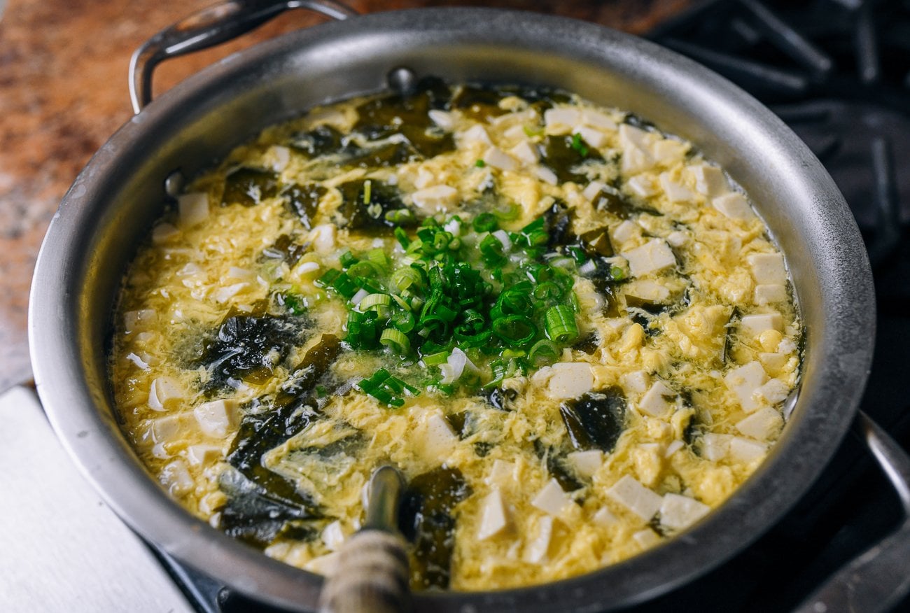 chopped scallion added to pot of miso soup