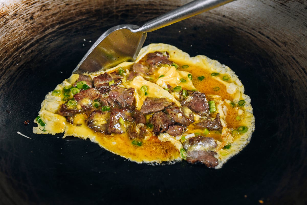 pushing egg and beef around wok with spatula
