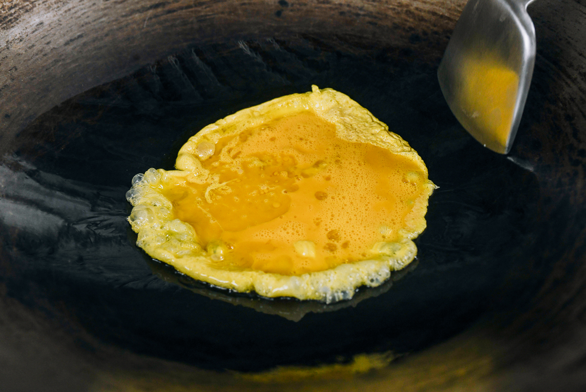 beaten eggs added to oil in a wok