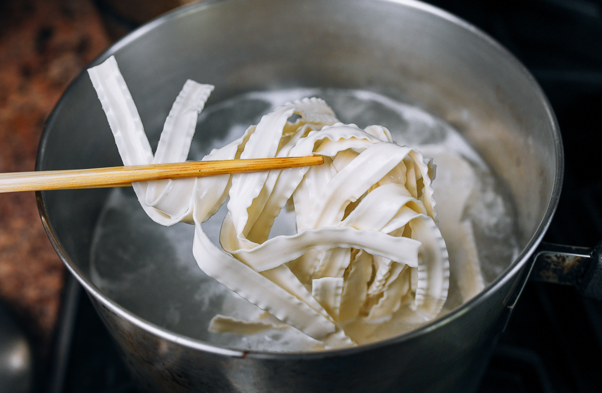 adding dried noodles to pot