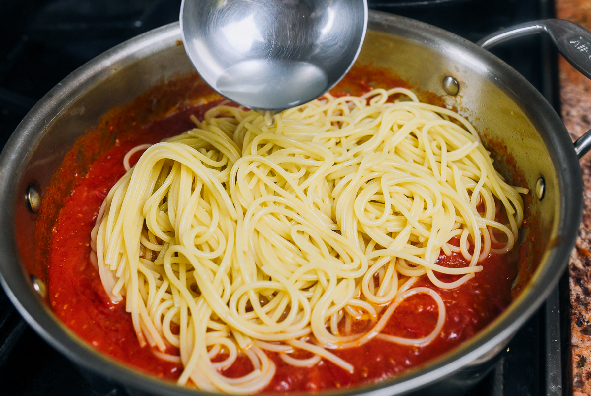 adding pasta water to spaghetti and tomato sauce