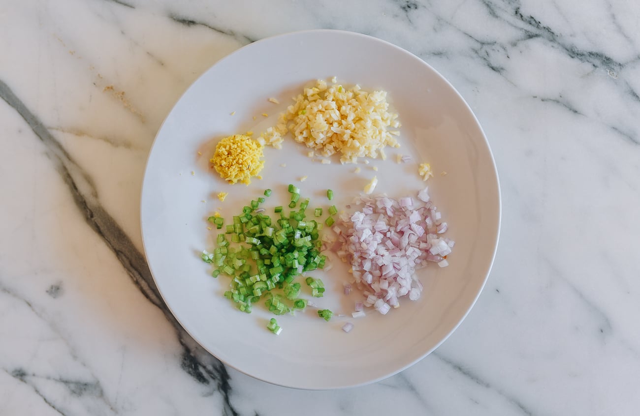 Plate of aromatics, including cilantro stems, ginger, garlic, and shallot