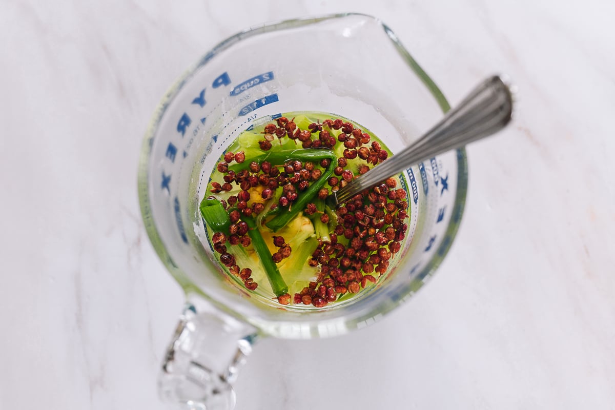 water infused with ginger, scallion, and sichuan peppercorns in measuring cup