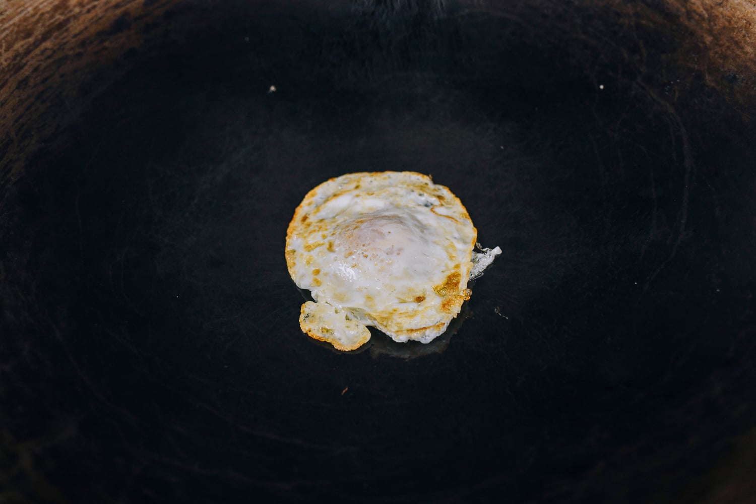 cooking over easy egg in wok