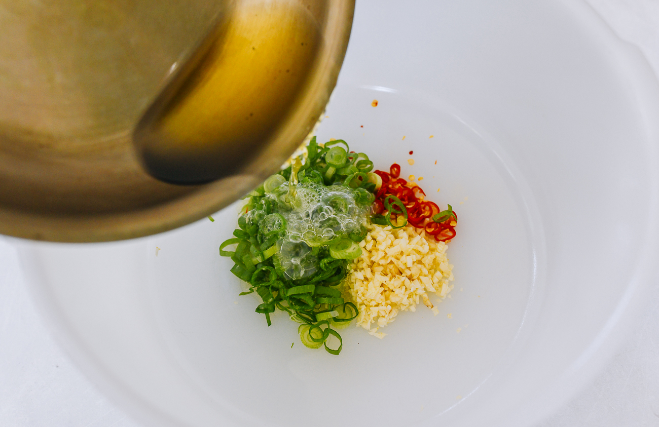 pouring hot oil over garlic, chili, and scallion