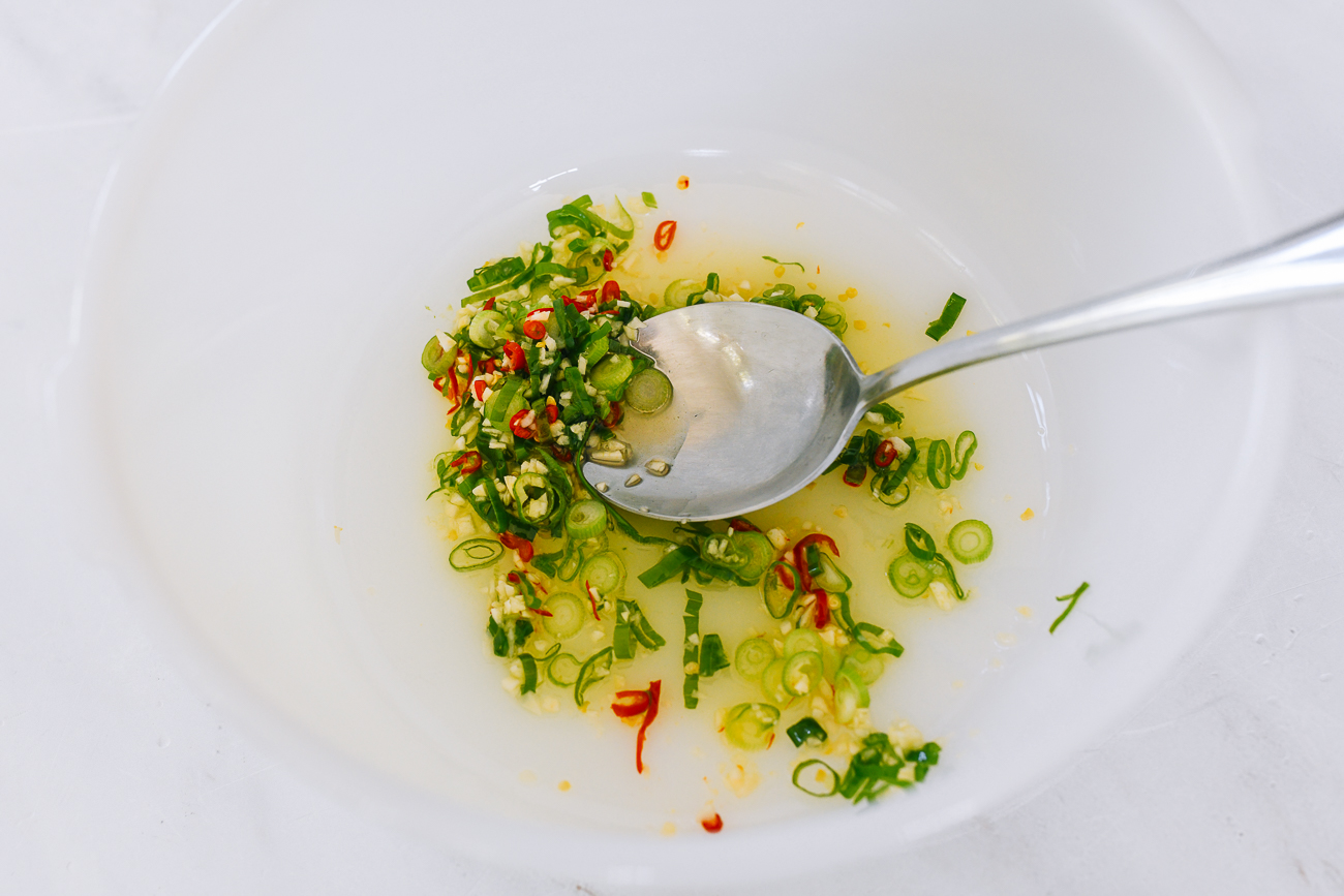 mixing hot oil with scallions, garlic and chilies