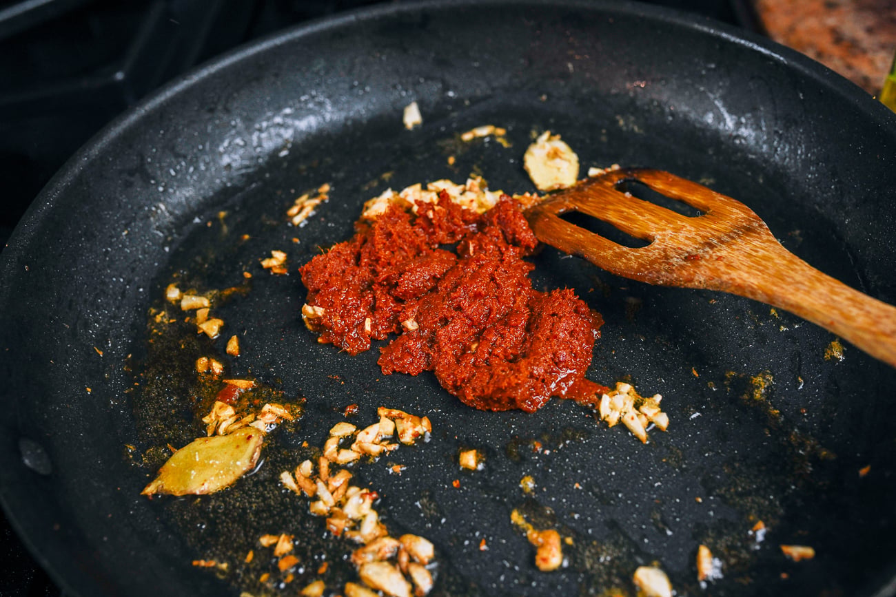 adding curry paste to pan with ginger and garlic