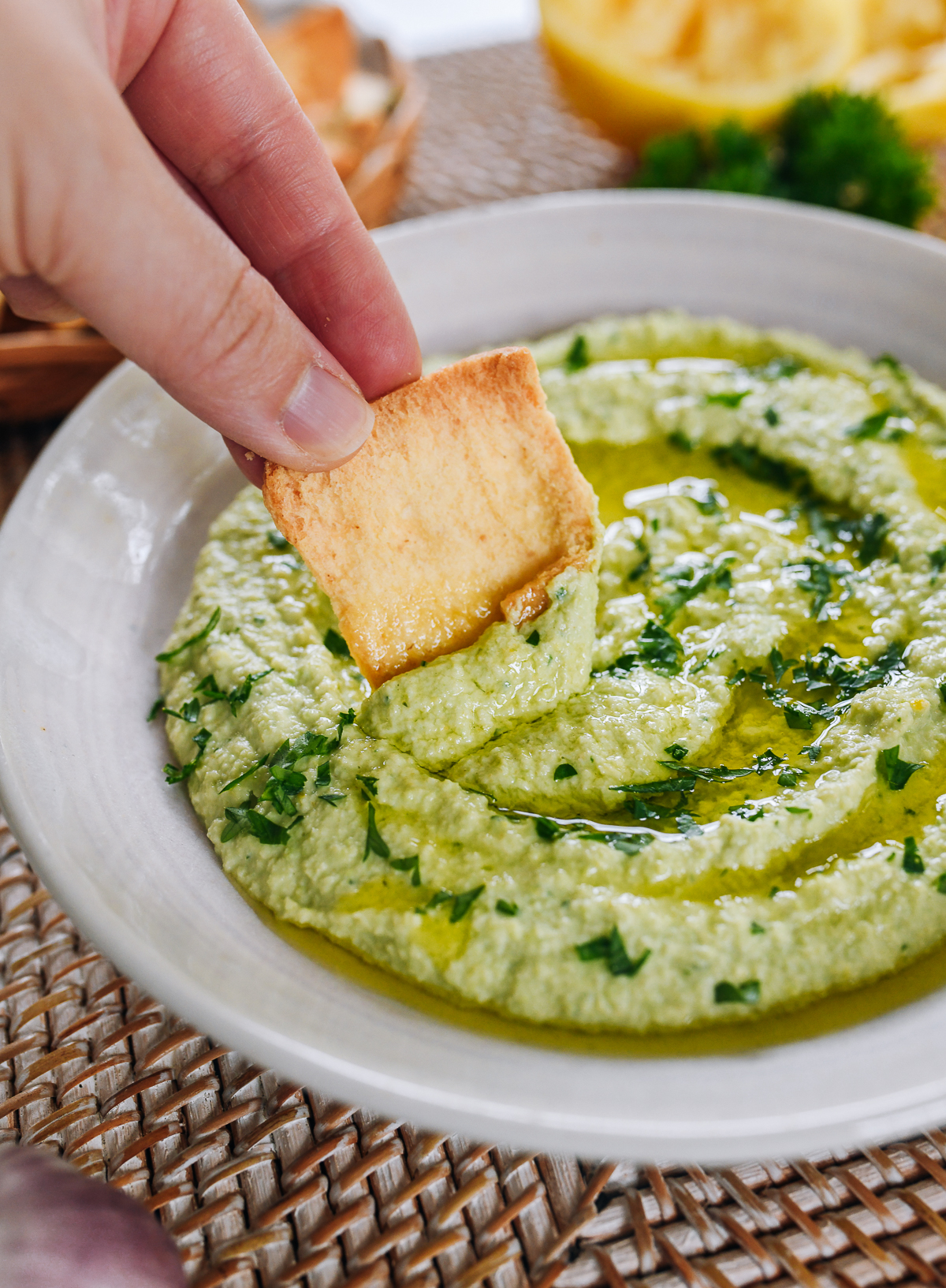 dipping pita chip into edamame hummus
