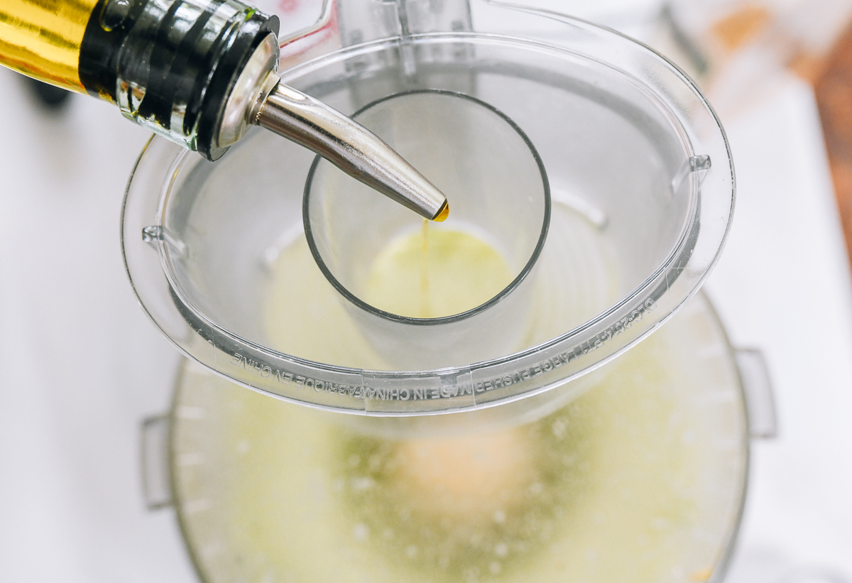 Pouring olive oil into running food processor