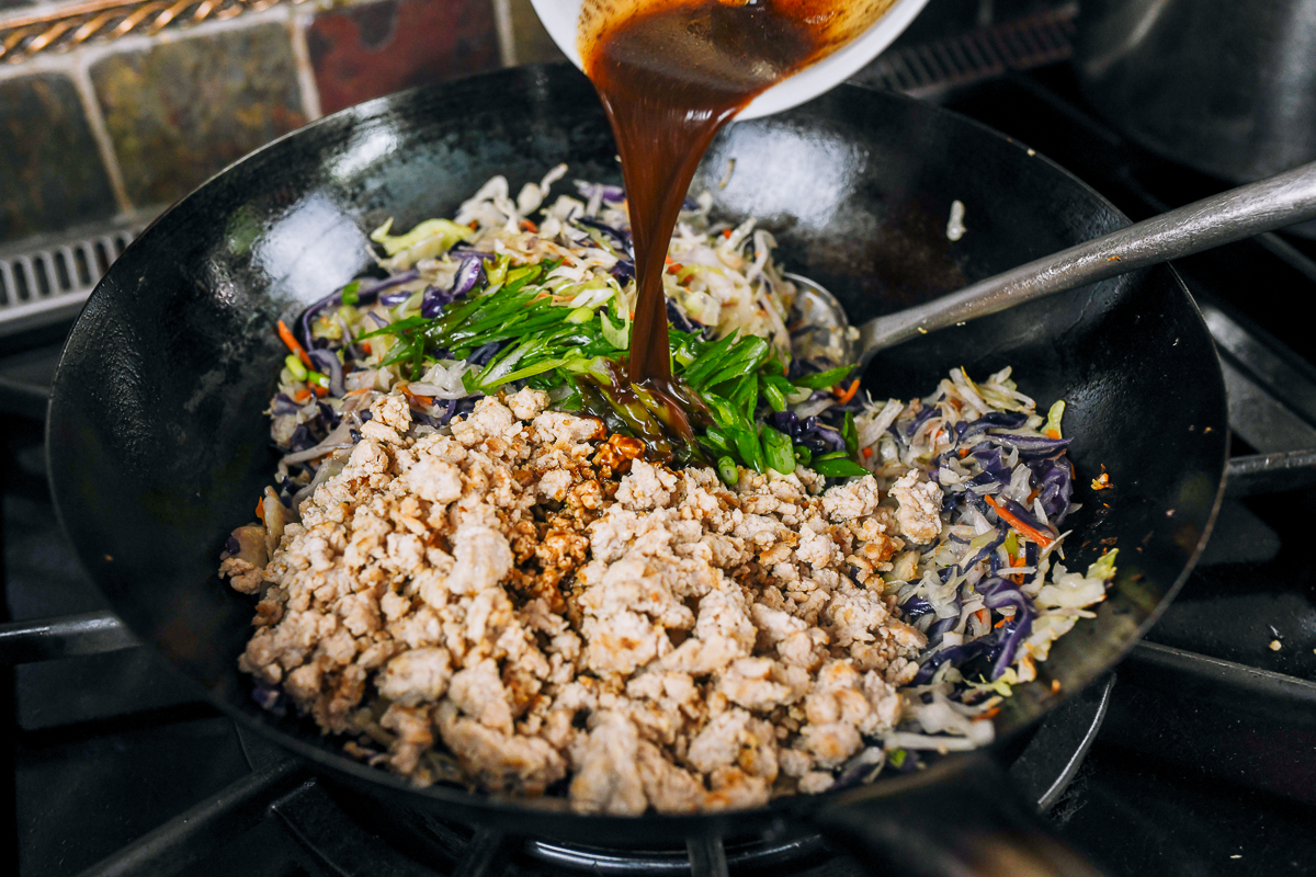 meat, scallions, and sauce added to egg roll bowl mixture in wok