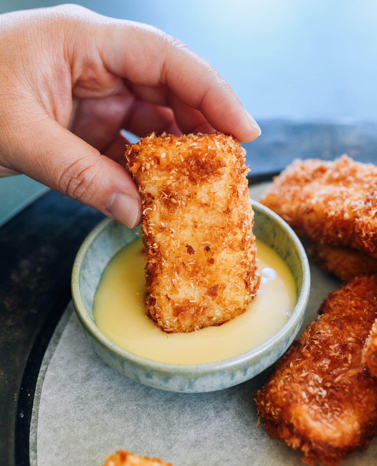 dipping fried milk into sweetened condensed milk
