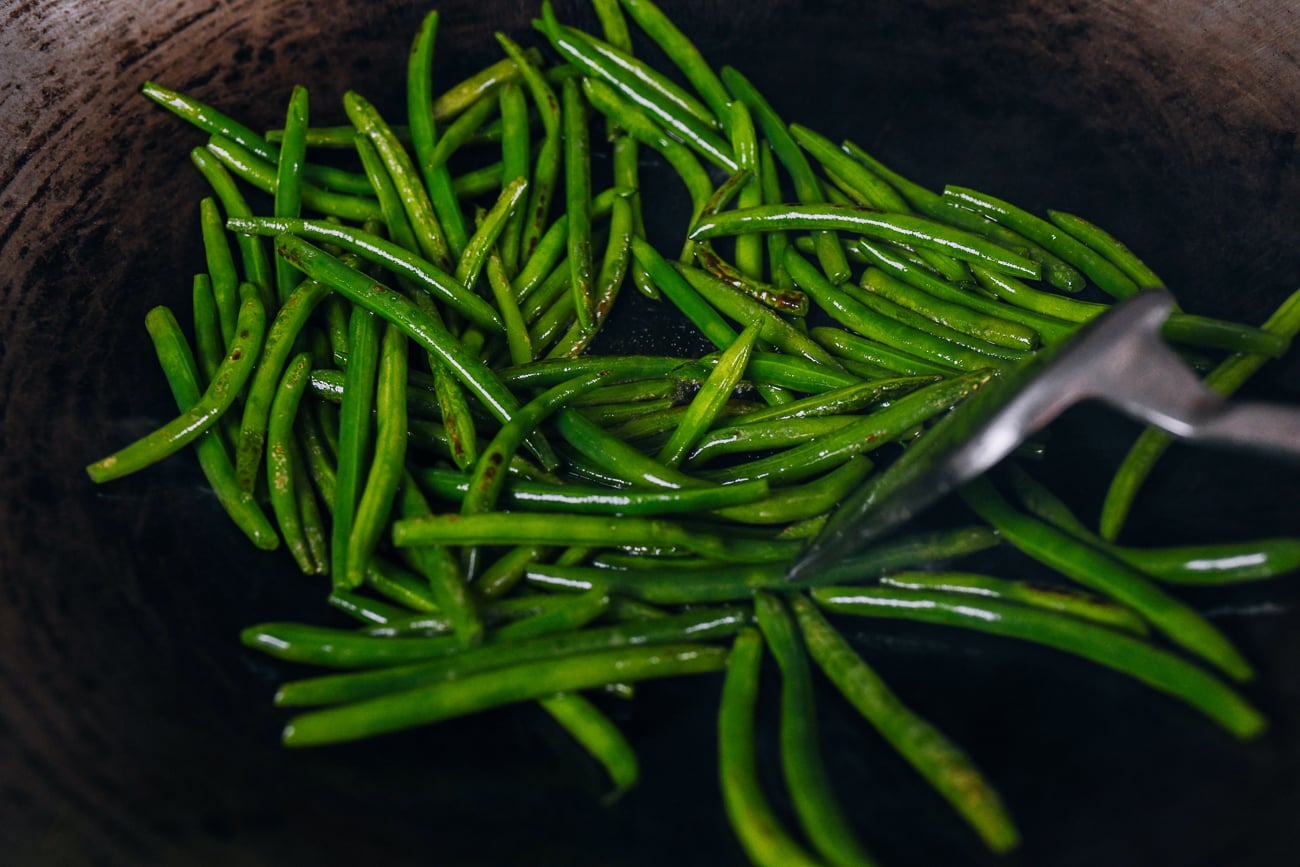 stir-frying green beans in a wok