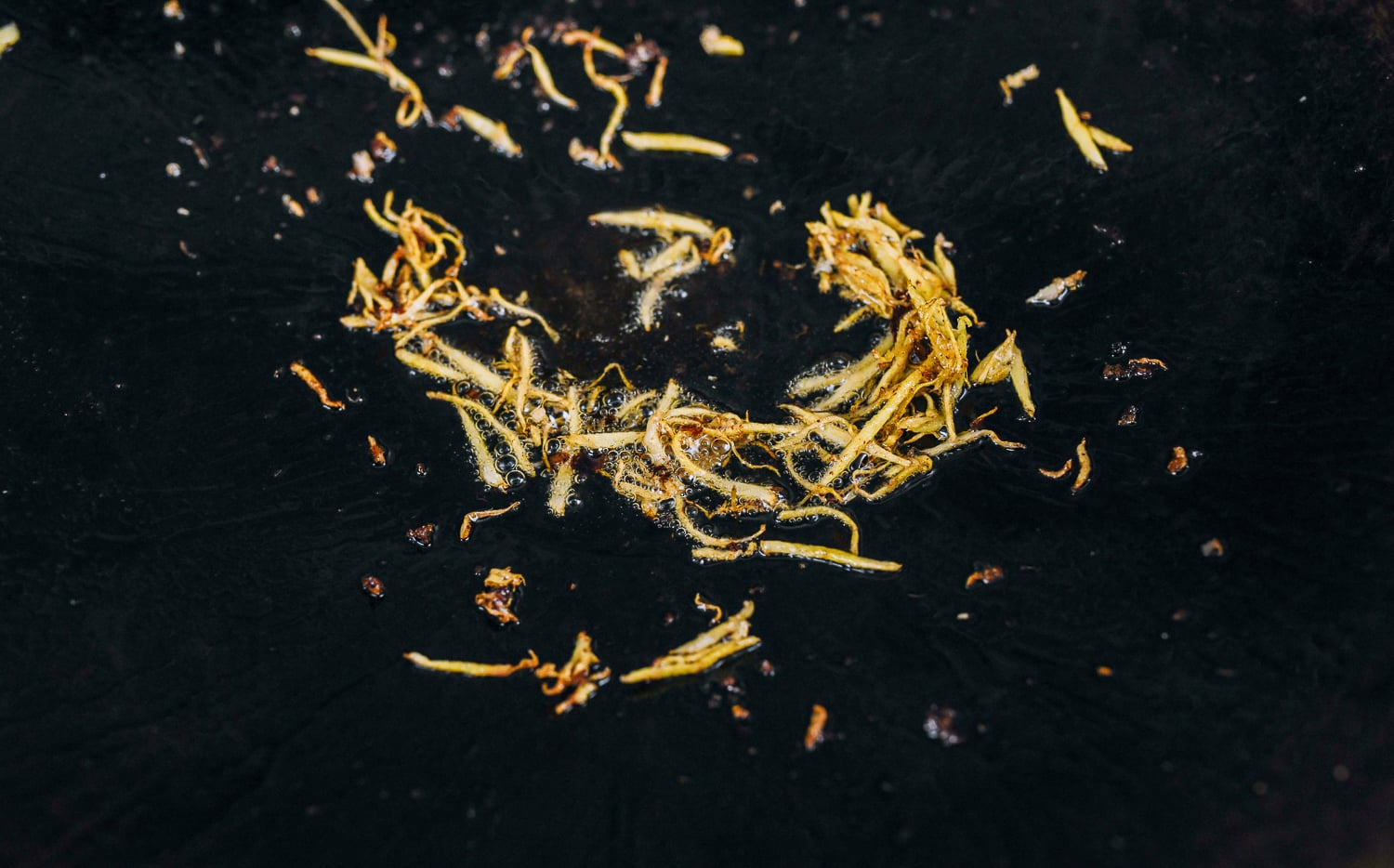 caramelized pieces of julienned ginger in a wok