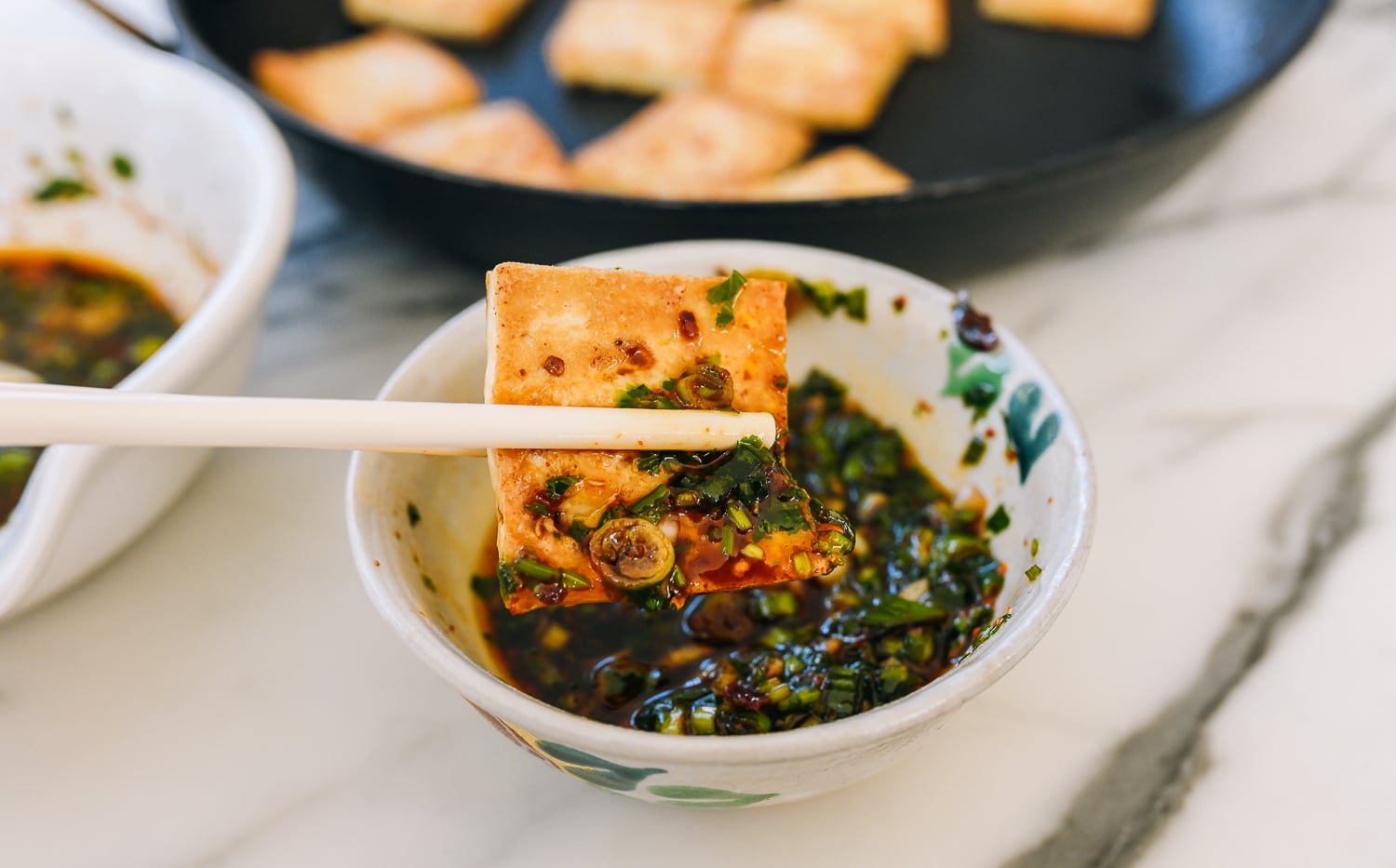 dipping pan-fried firm tofu into sauce