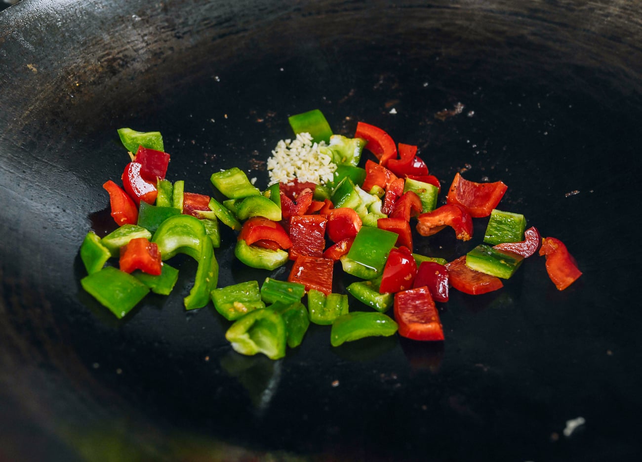 adding peppers and garlic to wok