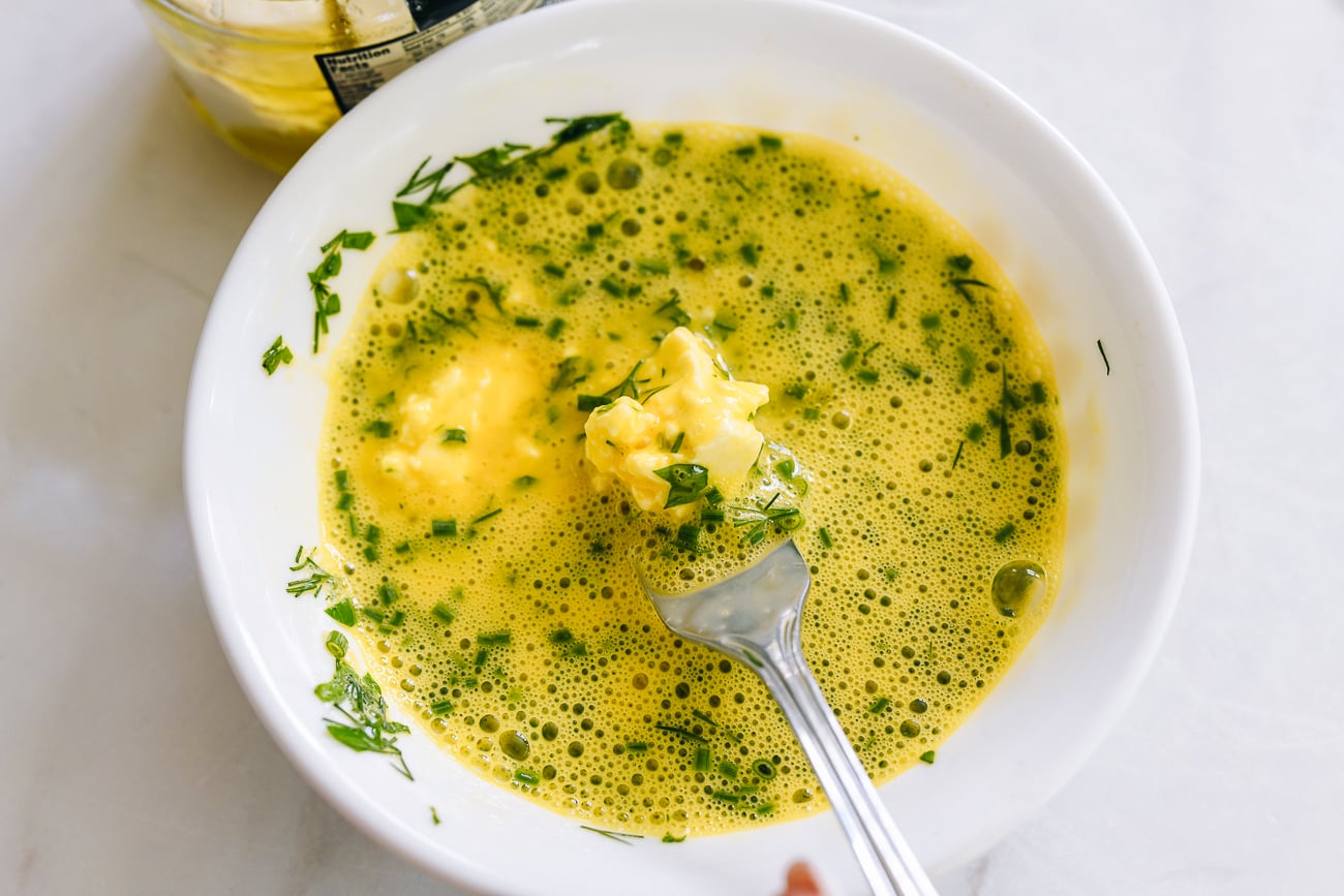 beating eggs with herbs and goat cheese