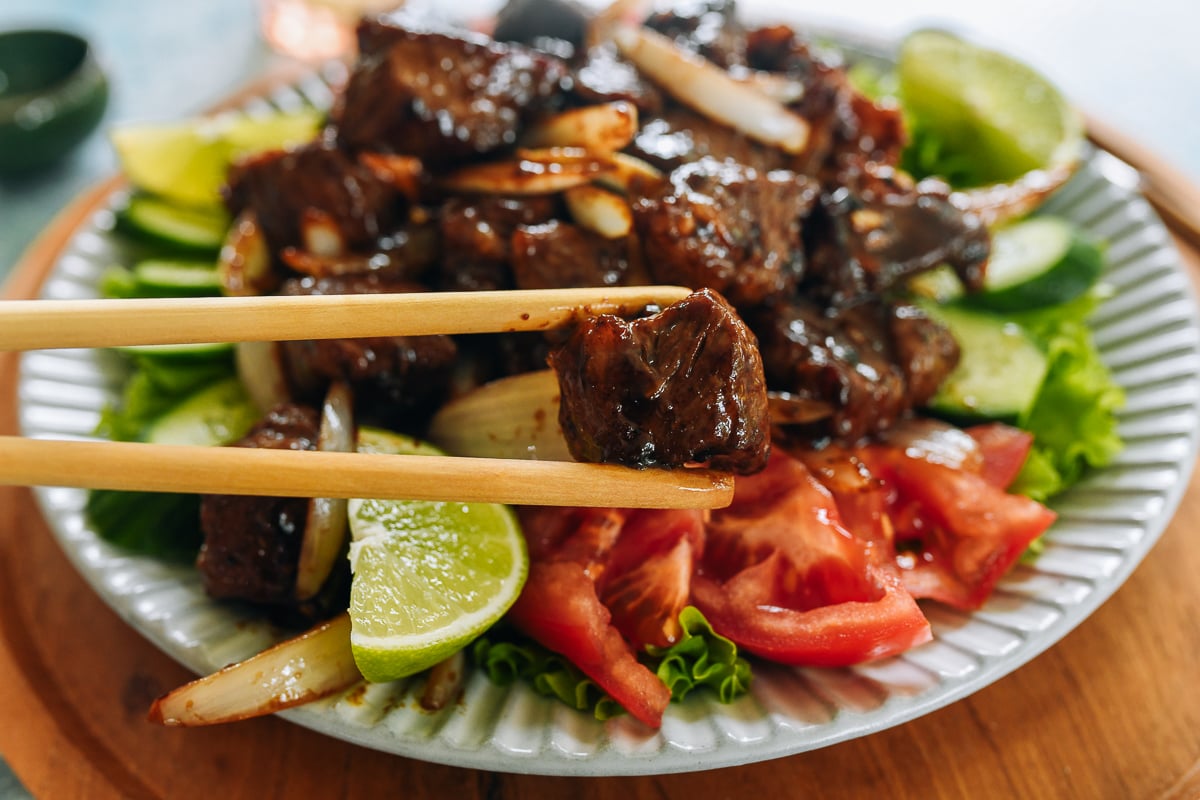 Picking up piece of Vietnamese shaking beef with chopsticks