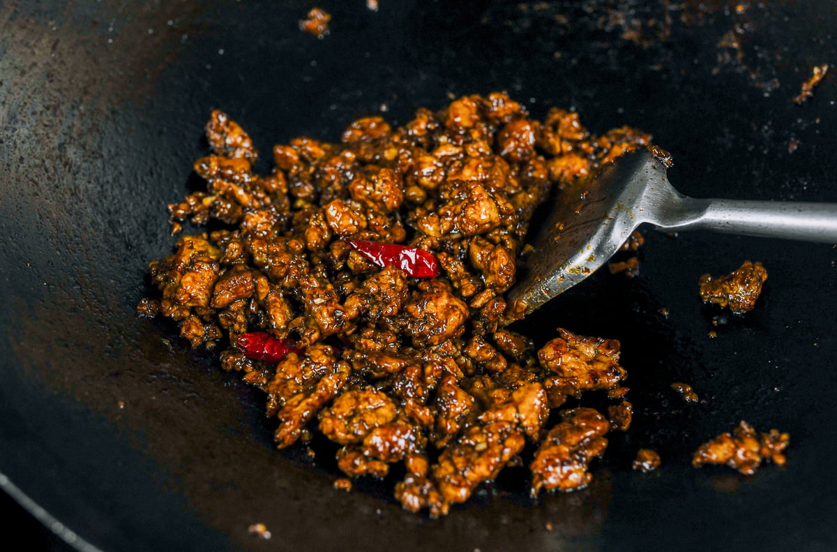stirring general tso's ground chicken in wok with sauce