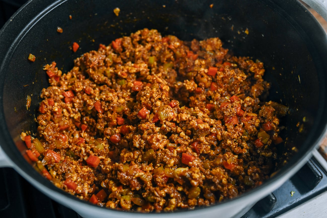 browned meat with finely chopped vegetables in pot