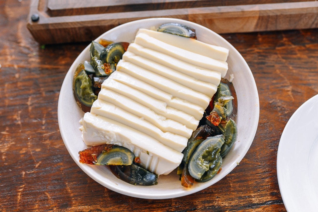 thousand year old egg slices around sliced soft tofu