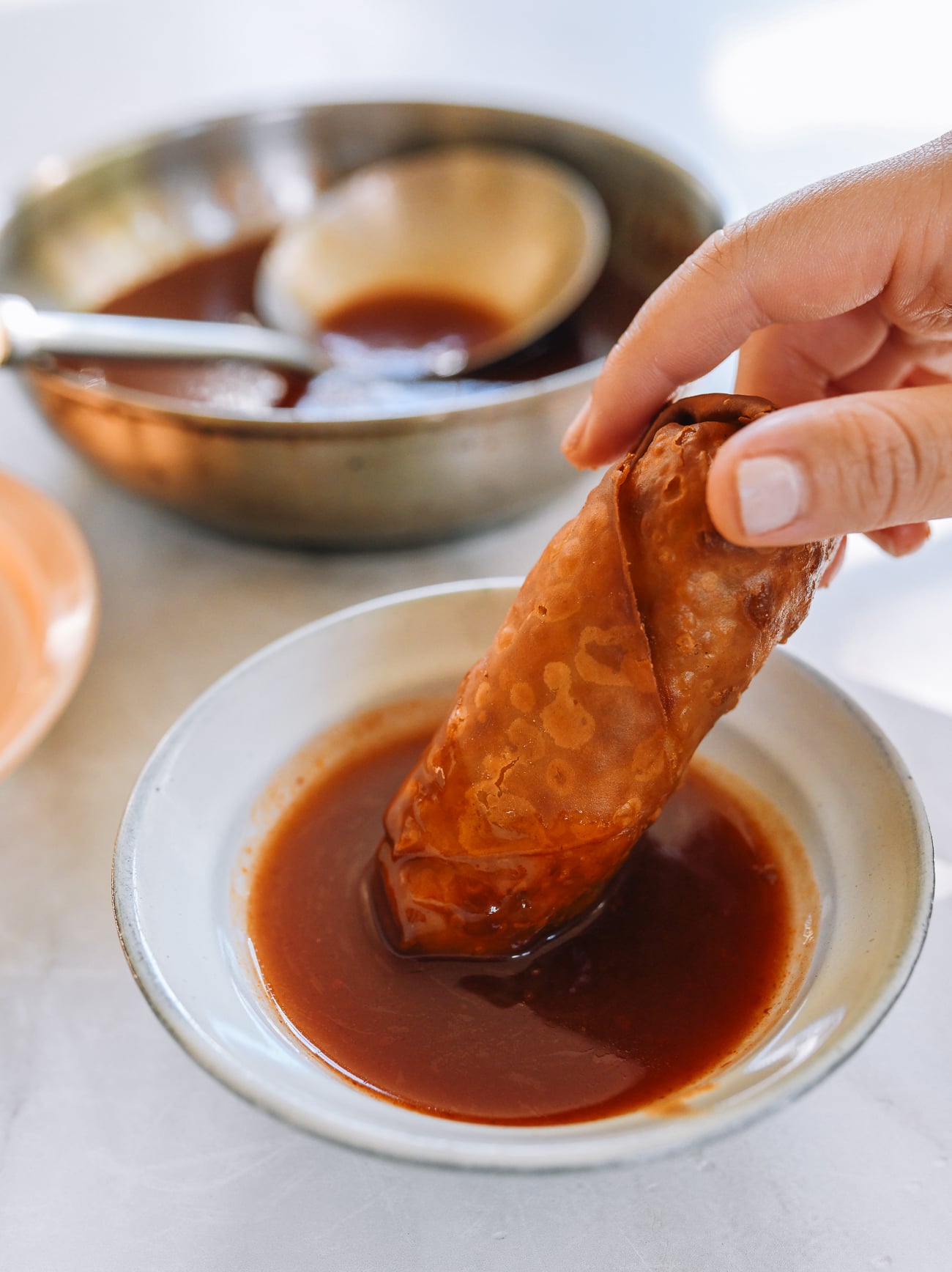 dipping egg roll into sweet and sour sauce