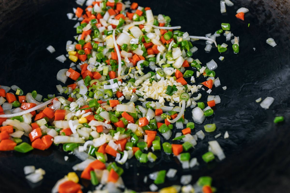 adding garlic and scallion whites to vegetables in wok
