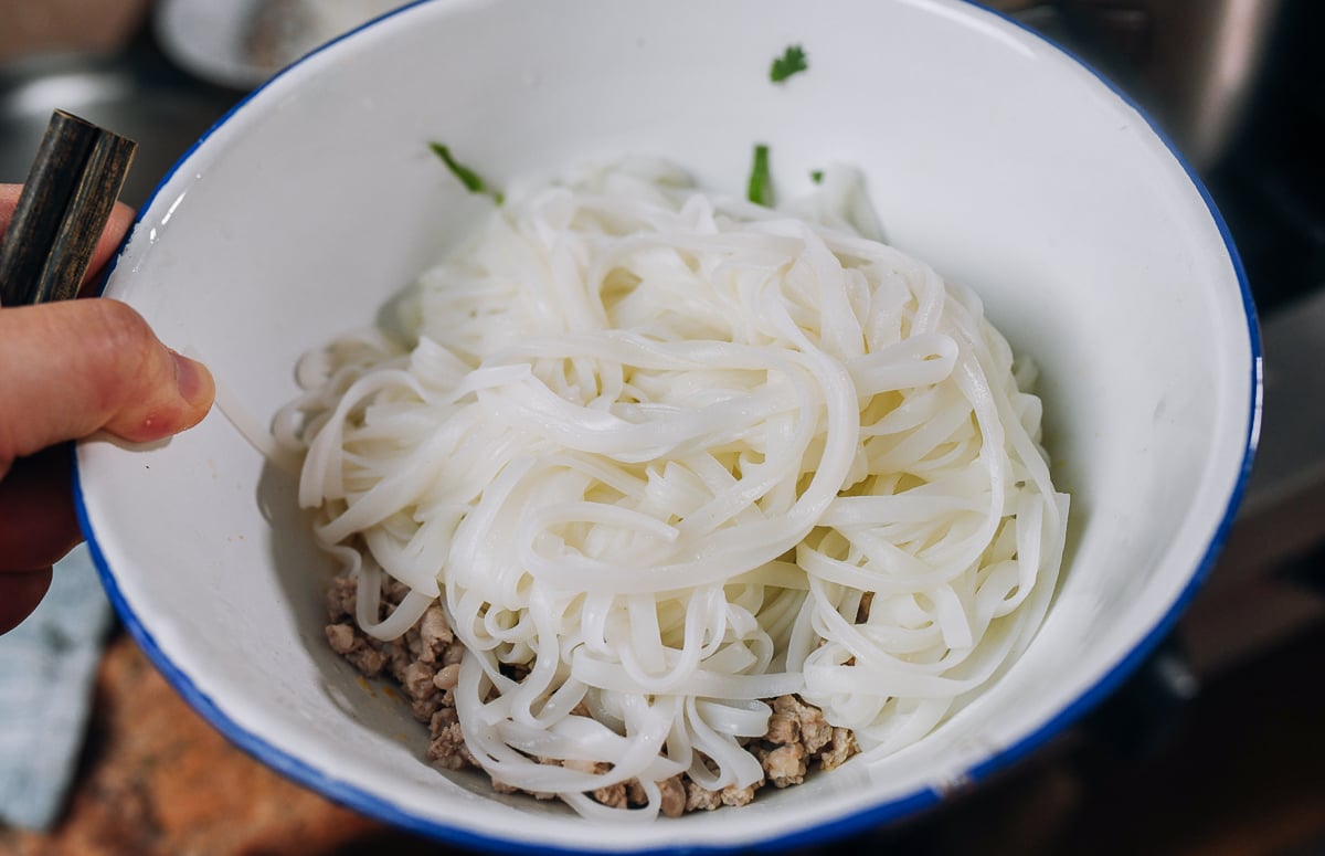 cooked rice noodles added to serving bowl with other ingredients