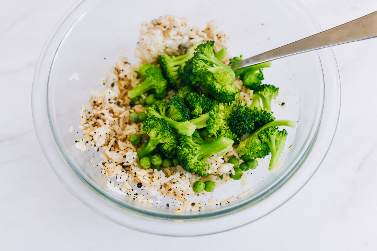 mixing rice, vegetables, and seasonings in glass bowl